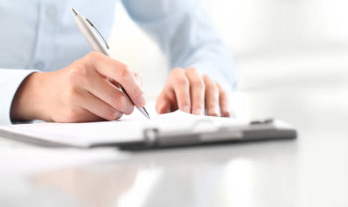 Hands holding pen and writing in paper