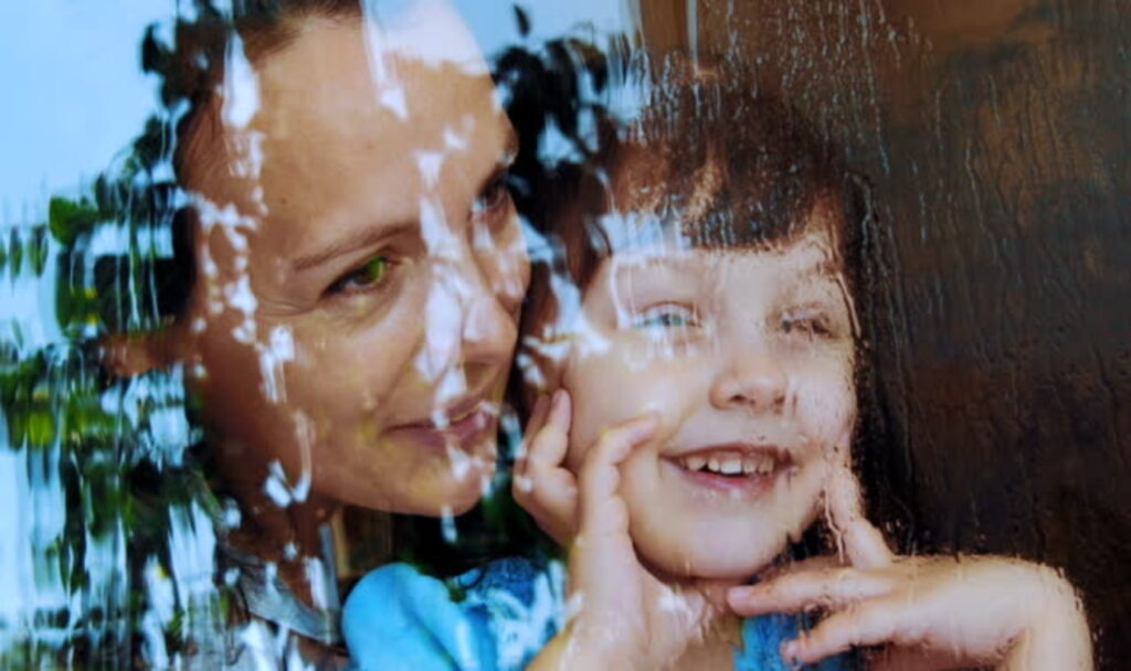 Woman and child enjoying rain indoors