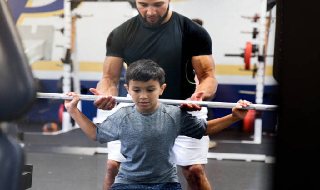 Men helping child in weightlifting