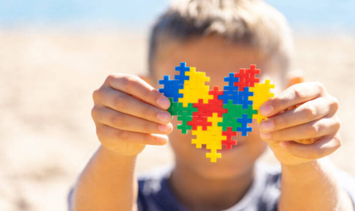 boy-holding-colorful-puzzle-heart in front of his face