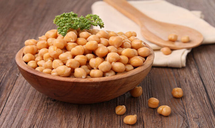 Chickpea in bowl topped with parsley in Wooden background