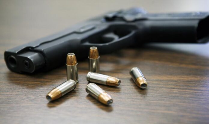 Gun and bullet on wooden background