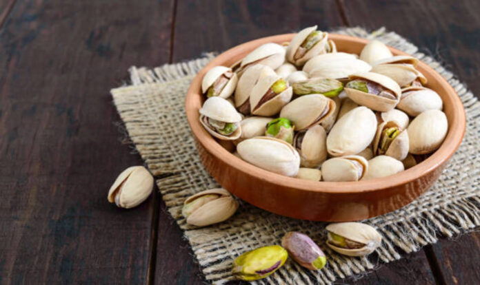 pistachios in bowl on wooden background