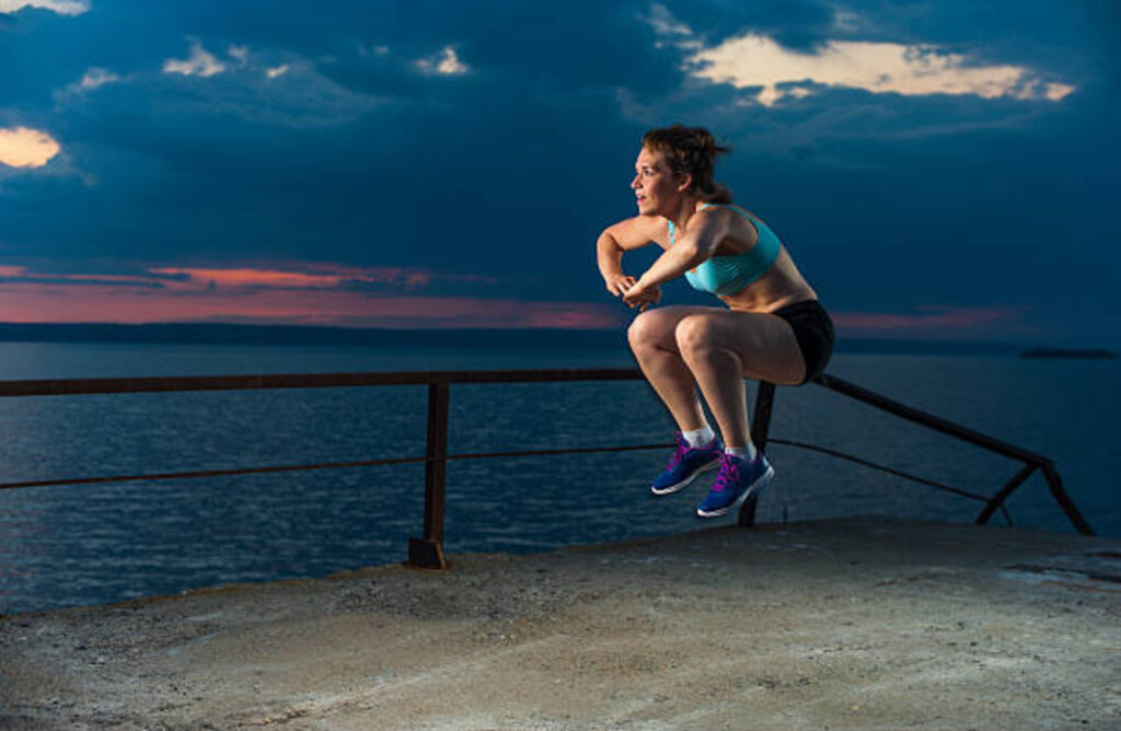 Woman doing tuck jumps outdoors
