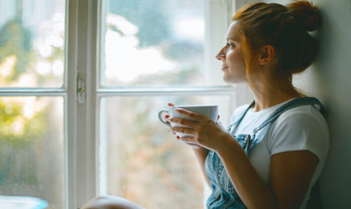 woman-is-looking-through-the-window-and-drinking
