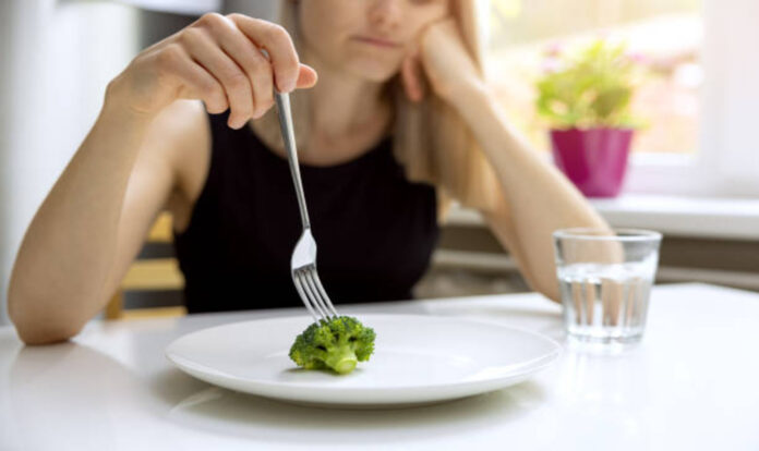 woman-looking-at-small-broccoli-portion-on-the-plate