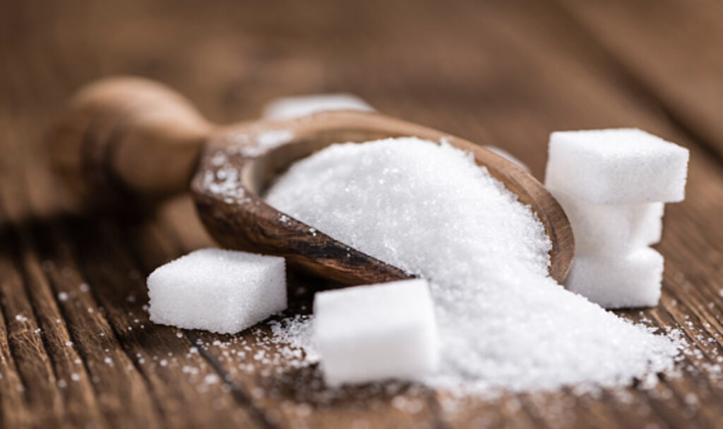 Sugar in a bowl and sugar cubes on wood